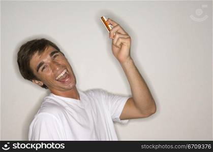 Portrait of a young man holding a mobile phone and laughing