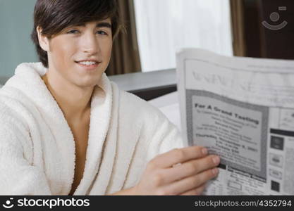 Portrait of a young man holding a newspaper