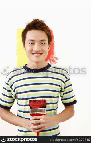 Portrait of a young man holding a paintbrush and smiling