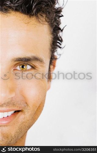 Portrait of a young man holding a paintbrush in front of his face and smiling