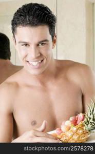 Portrait of a young man holding a plate of fruit