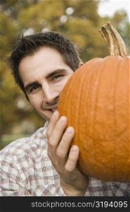 Portrait of a young man holding a pumpkin