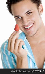 Portrait of a young man holding a strawberry