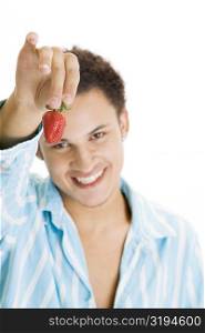 Portrait of a young man holding a strawberry