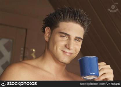 Portrait of a young man holding a tea cup and smiling