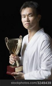 Portrait of a young man holding a trophy