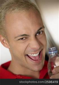 Portrait of a young man holding a water bottle and smiling