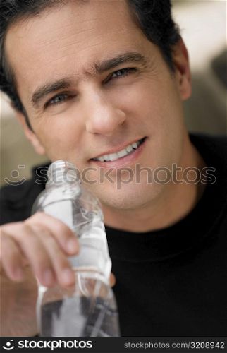 Portrait of a young man holding a water bottle and smiling