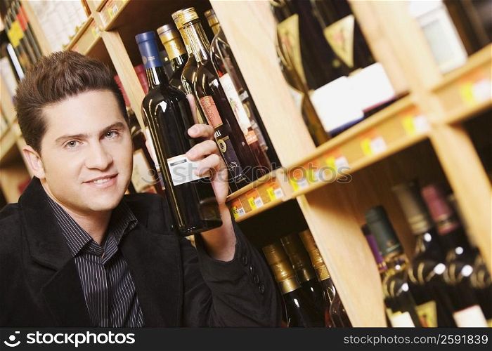 Portrait of a young man holding a wine bottle in a supermarket