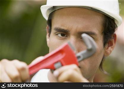 Portrait of a young man holding an adjustable wrench