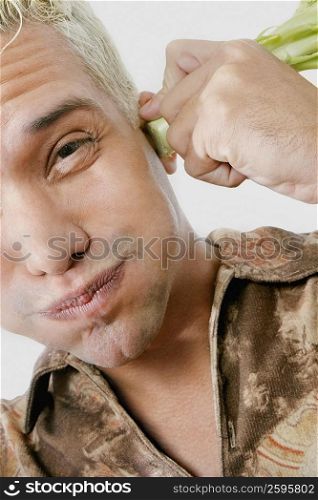 Portrait of a young man holding broccoli on his ears