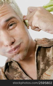 Portrait of a young man holding broccoli on his ears