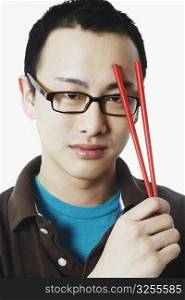 Portrait of a young man holding chopsticks