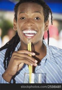 Portrait of a young man holding drinking straws