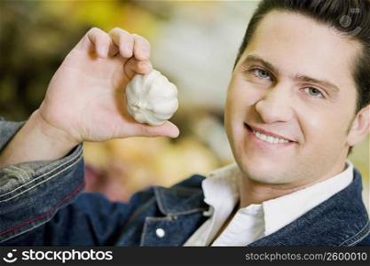Portrait of a young man holding garlic
