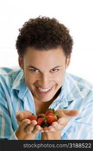 Portrait of a young man holding strawberries