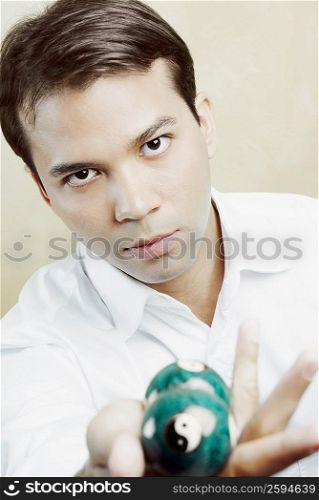 Portrait of a young man holding two pool balls