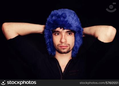 Portrait of a young man in a blue winter hat on a black background