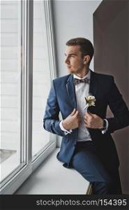 Portrait of a young man in a smart suit.. A man stands near a large window 6419.