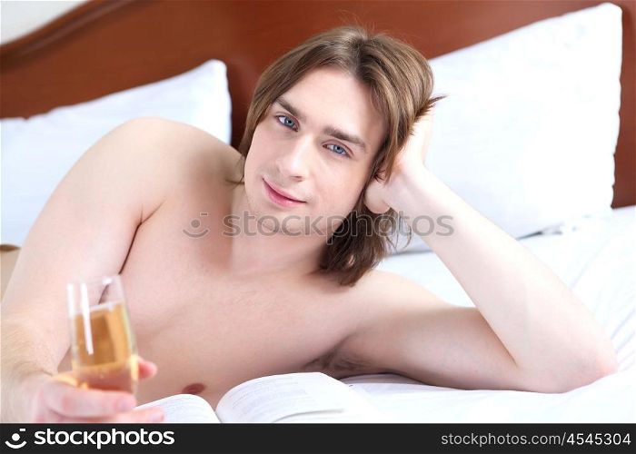 portrait of a young man in bed with a glass of campagne