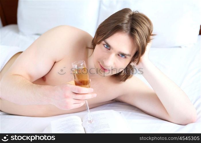 portrait of a young man in bed with a glass of campagne