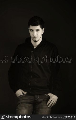 Portrait of a young man in the studio. Black and white. Hard light is applied to achieve an artistic effect.