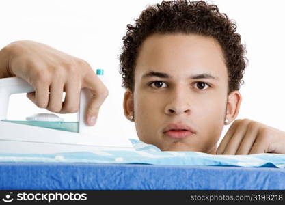 Portrait of a young man ironing his shirt