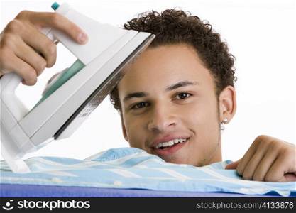 Portrait of a young man ironing his shirt
