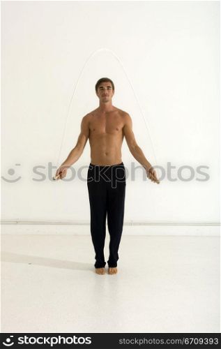 Portrait of a young man jumping with a jump rope