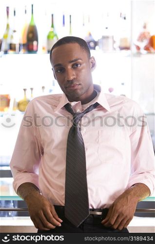 Portrait of a young man leaning against a bar counter