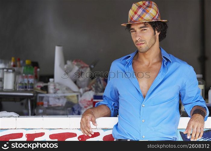 Portrait of a young man leaning against a bar counter of a juice bar
