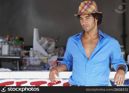 Portrait of a young man leaning against a bar counter of a juice bar