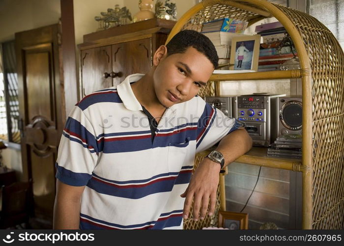 Portrait of a young man leaning against a shelf