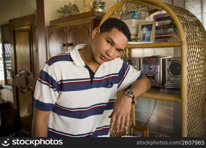 Portrait of a young man leaning against a shelf