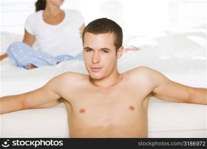 Portrait of a young man leaning against the bed