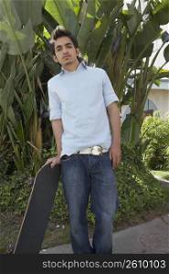 Portrait of a young man leaning on a skateboard