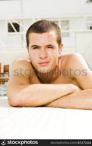 Portrait of a young man lying at the poolside