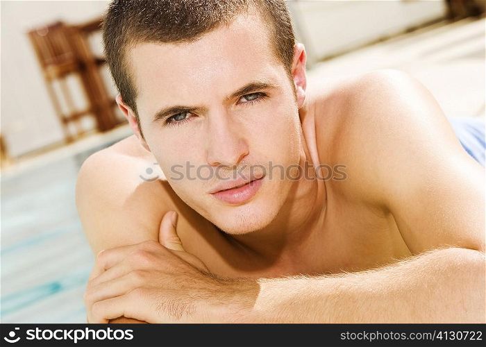 Portrait of a young man lying at the poolside