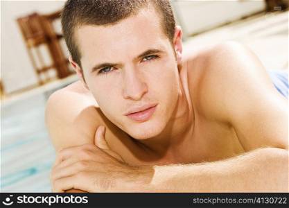 Portrait of a young man lying at the poolside