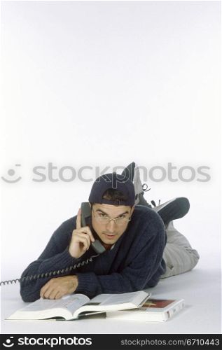 Portrait of a young man lying down talking on a telephone