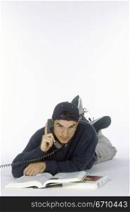 Portrait of a young man lying down talking on a telephone