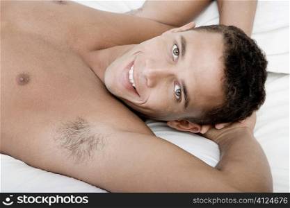 Portrait of a young man lying on a bed smiling