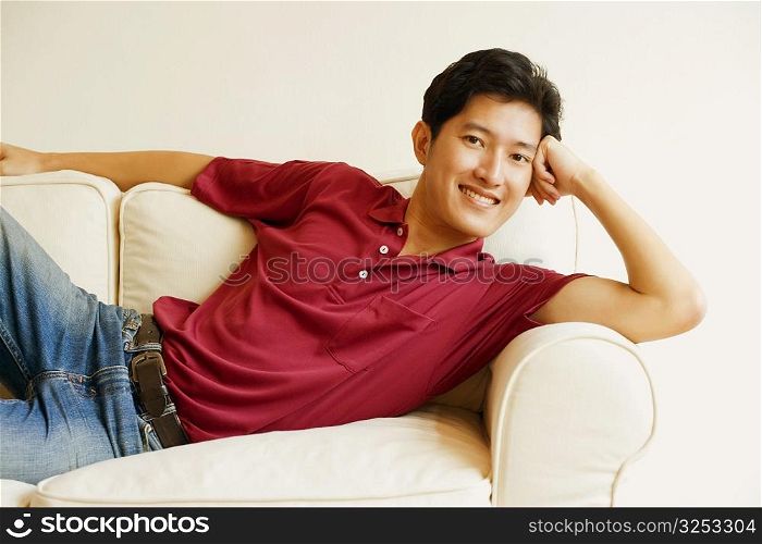 Portrait of a young man lying on a couch and smiling