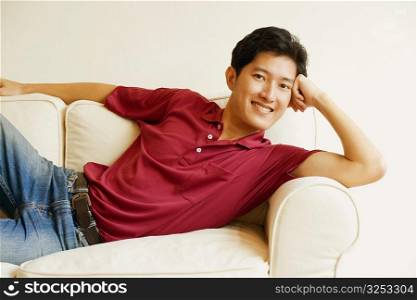 Portrait of a young man lying on a couch and smiling