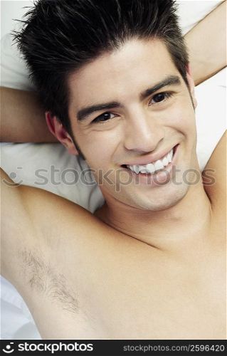 Portrait of a young man lying on the bed and smiling