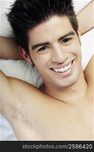 Portrait of a young man lying on the bed and smiling
