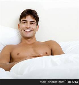 Portrait of a young man lying on the bed smiling