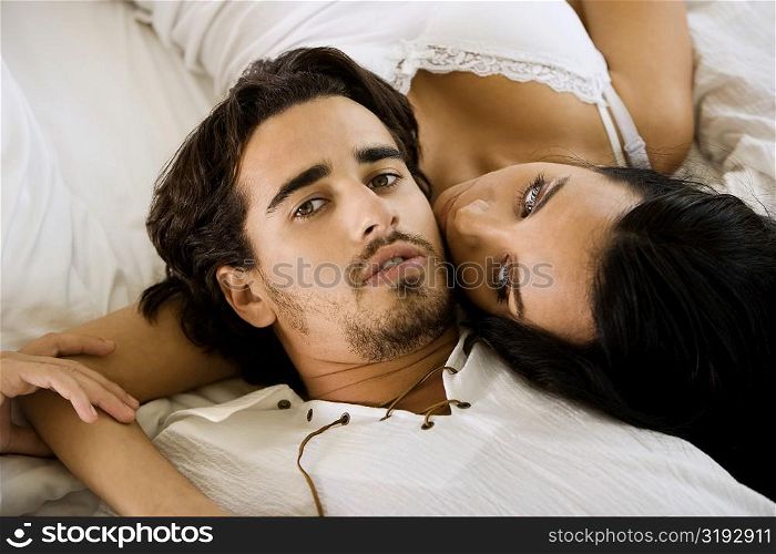 Portrait of a young man lying with a young woman on the bed