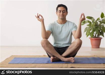 Portrait of a young man meditating at home