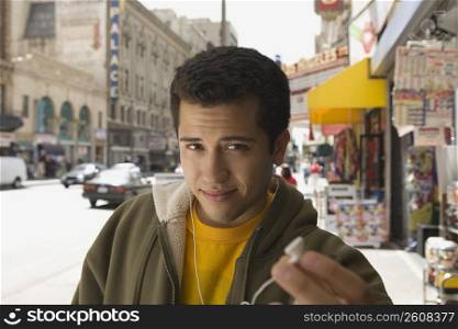Portrait of a young man offering an ear bud to listen music
